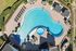 Townhomes at TSC Elegant aerial view of a luxurious outdoor swimming pool with cozy lounging areas, surrounded by lush greenery and stylish pavilions.