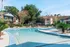 Townhomes at TSC Inviting outdoor pool area surrounded by lush greenery and modern apartment buildings, perfect for relaxation and leisure.