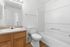 Townhomes at TSC Bright and modern bathroom featuring a sleek white bathtub, stylish vanity with ample storage, and elegant lighting.