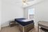 Townhomes at TSC Bright and airy bedroom with a cozy bed, desk, and ample natural light through large window, perfect for restful nights.