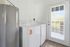 Townhomes at TSC Bright laundry room with modern washer and dryer, large water heater, and glass door leading to a sunny outdoor area.
