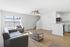 Townhomes at TSC Bright and airy living room with modern gray sofas, open kitchen concept, wood flooring, and elegant ceiling fan.