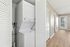 Townhomes at TSC Bright hallway featuring a modern in-unit laundry with stackable washer and dryer, sleek hardwood floors, and access to a private outdoor area through a glass door.