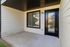 Townhomes at TSC Charming apartment exterior featuring a cozy covered patio with a sleek black-trimmed window and door, ideal for relaxation.