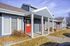 Charming blue townhouse exterior with bold red doors and welcoming covered porches, surrounded by well-maintained landscaping.