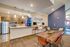 Contemporary community lounge featuring a stylish kitchen with stainless steel appliances, cozy seating area, and a rustic wooden table perfect for social gatherings.
