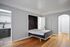 Modern apartment interior featuring a Murphy bed nestled in elegant hardwood flooring with a glimpse into a sleek, contemporary kitchen.