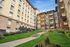 Elegant courtyard view of a historic apartment complex with lush green lawns, vibrant gardens, and classic architectural features.