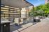 Chic outdoor patio area with modern fire pit, sleek barbecue station, and shaded seating under a stylish canopy, perfect for entertaining.