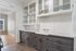 Charming kitchen with sleek black and white cabinetry, elegant subway tile backsplash, and a sunlit adjacent room with wooden flooring.