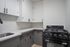 Chic modern kitchen featuring elegant white upper cabinets, contrasting dark lower cabinets, and a sleek black gas stove for a stylish cooking experience.