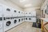 Modern laundry room with multiple high-efficiency washers and dryers, bright lighting, and spacious wooden flooring for convenience and comfort.
