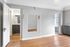 Elegant apartment interior with sleek wooden flooring, stylish wall accents, and modern lighting. A glimpse into a contemporary bathroom with a chic dresser and large mirror adds a touch of luxury.