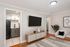Modern living room with sleek wall-mounted TV, elegant decor, and doorway leading to a compact stylish kitchen.