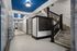 Elegant apartment lobby with marble walls, intricate iron staircase, and stylish mailbox area. Vibrant lighting creates a welcoming atmosphere.