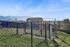 Scenic apartment view with fenced play area, lush green grass, and stunning mountain backdrop.