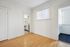 Bright, spacious room with polished hardwood floors, a glimpse of a modern bathroom, and ample natural light through large windows.