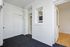 Bright and pristine entryway with white walls, carpeted floor, and inviting open door leading to light wood flooring.