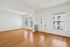 Bright and inviting living space featuring elegant hardwood floors, ample natural light, and chic vertical blinds.