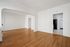 Bright and inviting empty living space with elegant hardwood floors and an open archway leading to the kitchen.