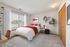 Bright and inviting bedroom with a cozy bed, ample natural light, and modern decor. Perfect for relaxation and comfort.