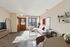 Bright and inviting living room with modern decor, cozy white sectional sofa with red pillows, stylish coffee table, and large window allowing natural light to fill the space. Perfect for relaxation or entertaining.