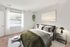 Bright and inviting bedroom with large window, modern decor, and lush green accents.