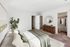 Inviting bedroom with natural lighting, plush bedding, large walk-in closet, and stylish decor, perfect for relaxation.