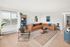 Bright and inviting living room featuring a stylish L-shaped sofa, modern decor, and natural light streaming through large windows.