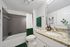 Elegant bathroom featuring a granite countertop, modern fixtures, luxurious green accents, and a tiled bath area.