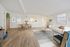 Inviting open-plan living room and dining area with modern decor, featuring a plush cream sofa, stylish armchairs, and elegant wood flooring, bathed in natural light.
