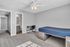 Bright and inviting bedroom with soft carpeting, featuring a modern bed, study desk, and an attached bathroom, perfect for relaxation and productivity.