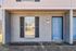 Charming apartment exterior featuring a stylish blue door, classic brick facade, and modern window with elegant shutters.