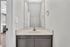 Bright and modern bathroom with sleek cream countertop, large mirror, and subtle gold accents.