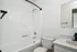Modern white bathroom with elegant bathtub, sleek vanity, and large mirror for a refreshing experience.
