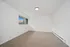 Bright, minimalist bedroom with plush carpeting and large window offering natural light.