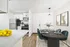 Elegant open-plan kitchen and dining area with modern stainless steel appliances, chic white cabinets, and a stylish dark dining table set with classy dinnerware.