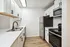 Modern kitchen featuring sleek white cabinets, stainless steel appliances, and elegant hardwood flooring.