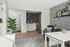 Modern living area featuring a stylish dining table, cozy blue armchair, and sleek decorative shelving. Bright, inviting space with elegant wood flooring and vibrant green potted plant, perfect for relaxation and entertaining.