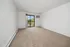 Bright room with plush carpet, white walls, and a large window sliding door leading to a scenic balcony view.