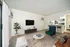 Chic modern living room with stylish furniture, large TV, and cozy open-concept kitchen in a bright, inviting apartment.