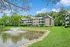 Charming apartment complex nestled in lush greenery, featuring serene pond with a sparkling fountain.