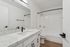 Modern bathroom featuring a sleek marble countertop, minimalist white cabinetry, and elegant black fixtures.