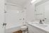 Sleek modern bathroom with elegant white fixtures, a luxurious bathtub, and a spacious marble countertop.