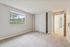 Bright and airy bedroom with plush carpeting, large window offering garden views, and sliding closet doors, perfect for comfortable living.