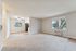 Bright and airy living space with plush carpeting, large windows, and modern kitchen area, creating a welcoming and comfortable environment.