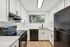 Modern kitchen with sleek white cabinetry, marble countertops, and black appliances, offering a blend of style and functionality.