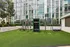 Modern outdoor fitness area with sleek gym equipment against a backdrop of a stylish glass building, surrounded by lush greenery.
