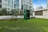 Modern outdoor fitness area with lush greenery, exercise equipment, and a sleek high-rise backdrop.