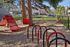 Inviting outdoor playground with vibrant red equipment and lush greenery, perfect for family fun.